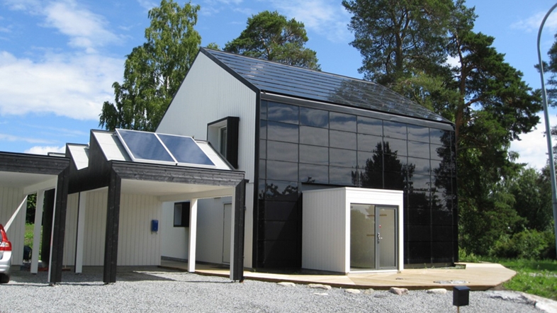Ett hus som är byggt med solceller, från tak till vägg, en solig sommardag. 