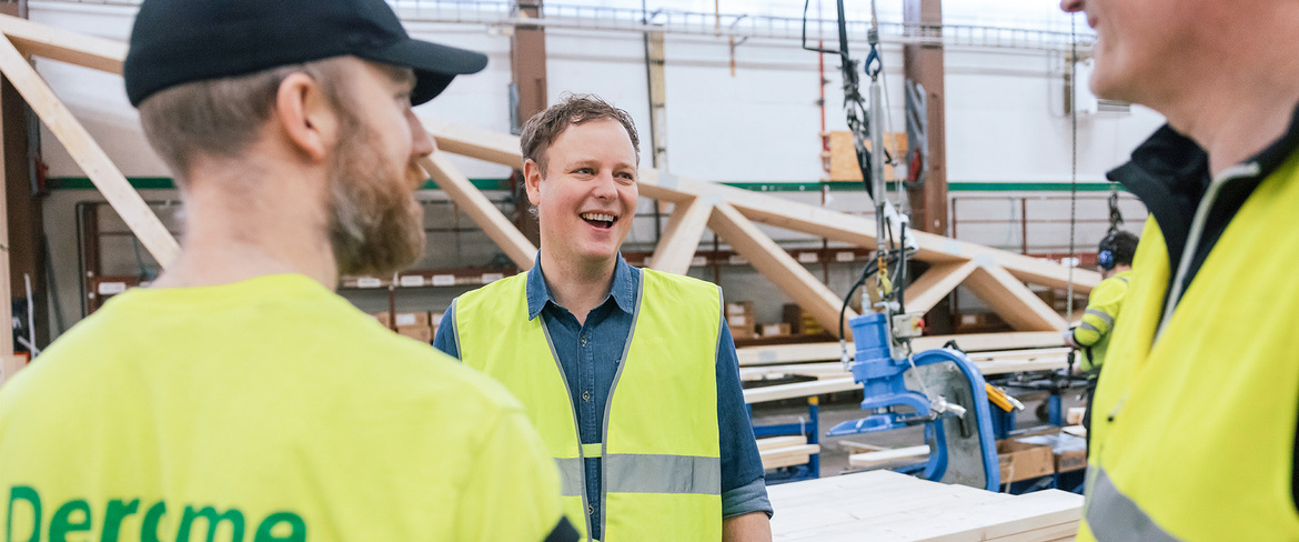 Fyra män i varselkläder inne i en takstolsfabrik. 