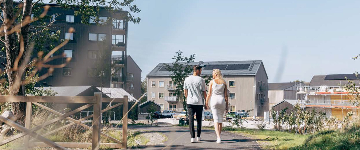 En man och en kvinna går och håller handen i ett bostadsområde. 