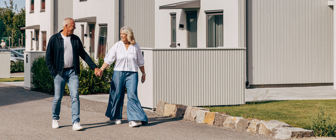 En man och en kvinna går igenom ett bostadsområde hållandes i varandras händer. 